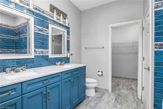 a spacious bathroom with a granite countertop toilet a sink and a mirror