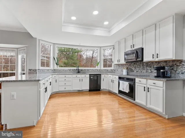 a kitchen with stainless steel appliances granite countertop a stove top oven a refrigerator a sink and a dining table with wooden floor