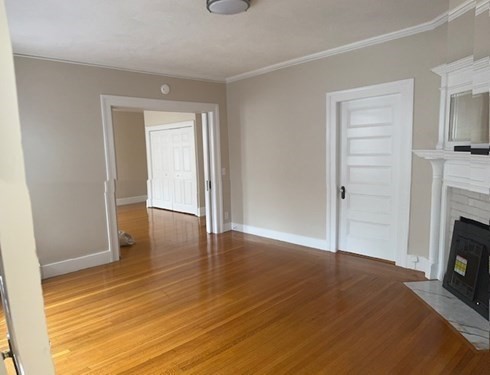 7 Lowell Street, Unit A Woburn, MA 01801 - Photo 6 of 17 an empty room with wooden floor fireplace and staircase