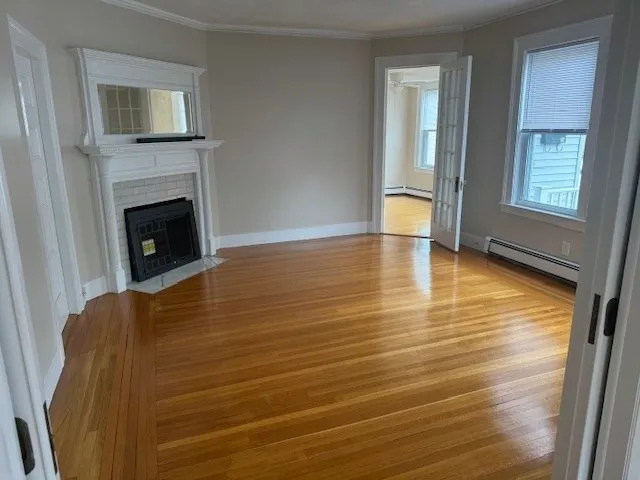 a view of an empty room with glass door and wooden floor