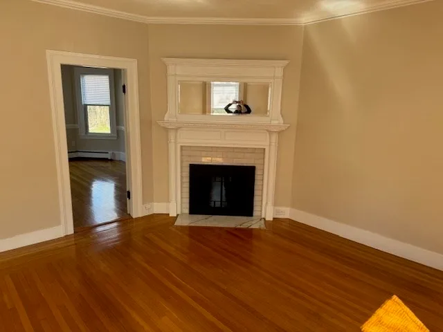 a view of an empty room with wooden floor and a fireplace