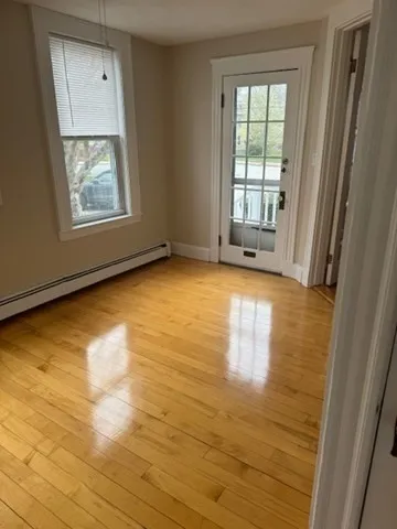 a view of an empty room with a window and wooden floor