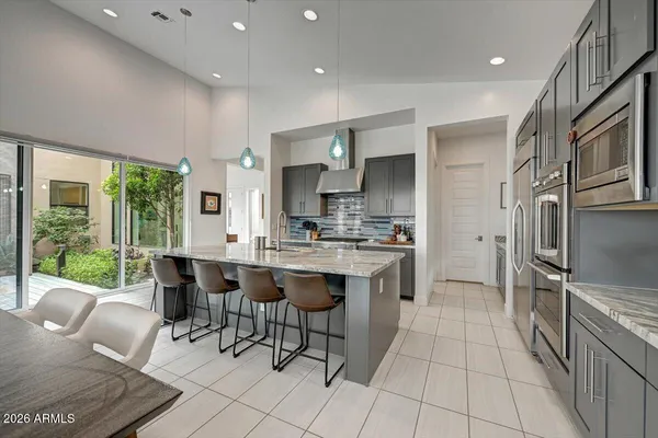 a kitchen with stainless steel appliances kitchen island granite countertop a refrigerator and a sink