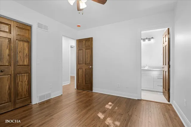 an empty room with wooden floor cabinet and windows
