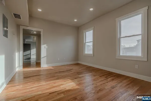 an empty room with wooden floor and windows
