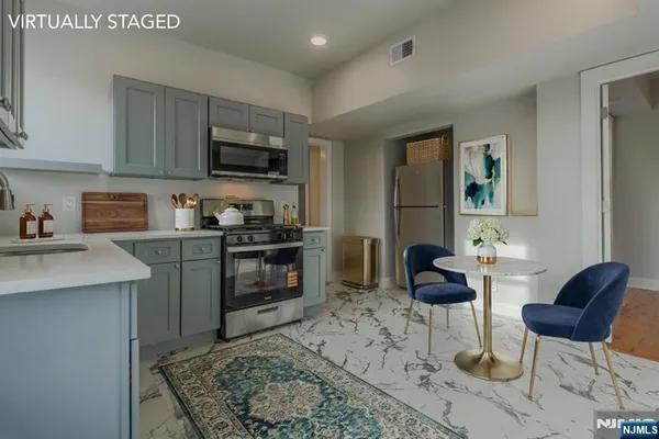 a kitchen with stainless steel appliances granite countertop a stove top oven a sink a dining table and chairs