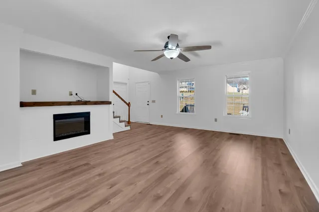 an empty room with wooden floor fireplace and windows