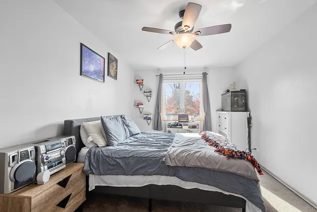 a bedroom with a bed ceiling fan and a window