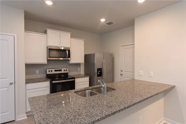 a kitchen with stainless steel appliances granite countertop a sink stove and refrigerator