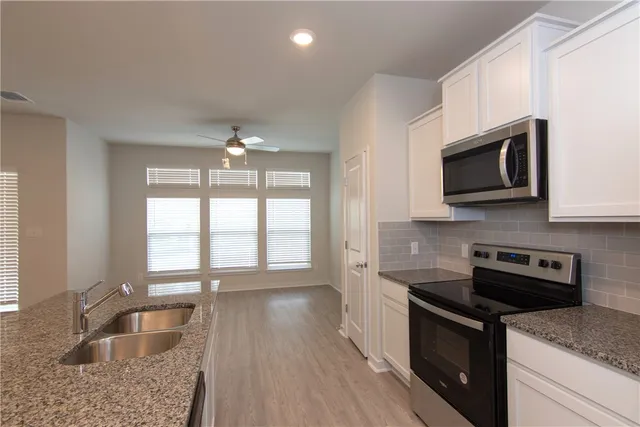 a kitchen with granite countertop wooden cabinets stainless steel appliances and a window