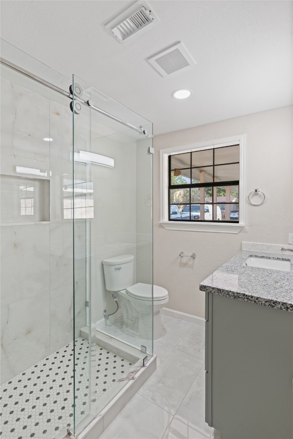 10613 Chadwick Street Houston, TX 77029 - Photo 21 of 30 a bathroom with a granite countertop sink a toilet a mirror and shower