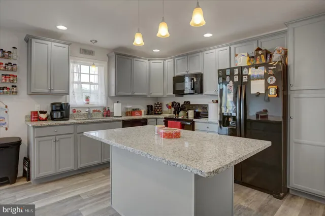 a kitchen with stainless steel appliances granite countertop a sink a refrigerator and a stove top oven
