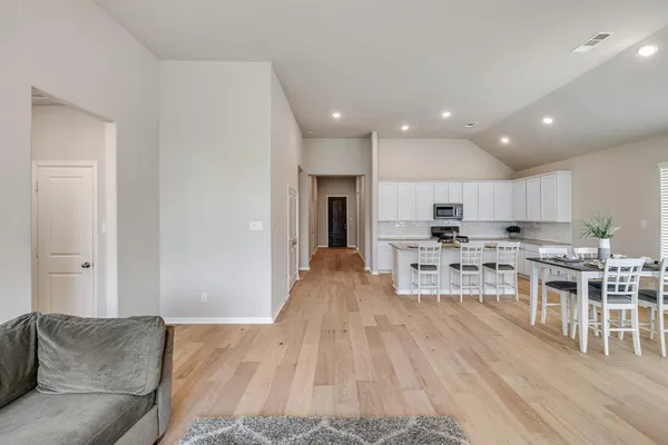 a living room with stainless steel appliances granite countertop furniture wooden floor and a view of kitchen