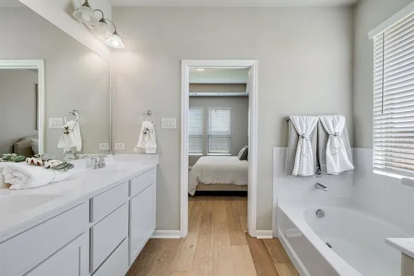 a en suite spacious bathroom with a tub double vanity and view bedroom