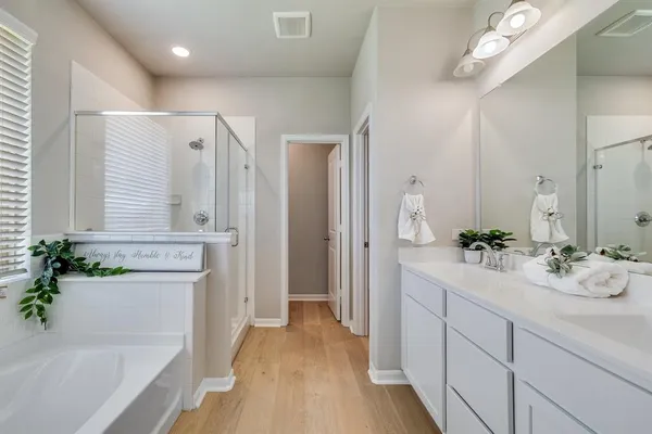 a spacious bathroom with a double vanity sink a mirror a bathtub and next to a window