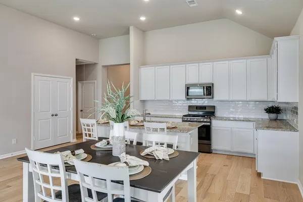 a kitchen with a dining table chairs and white appliances