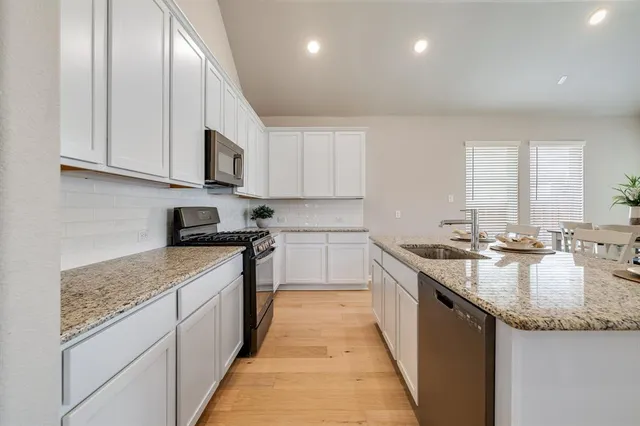 a living room with stainless steel appliances granite countertop furniture wooden floor and a view of kitchen