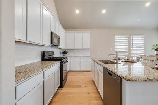 a kitchen with stainless steel appliances granite countertop a sink stove and cabinets