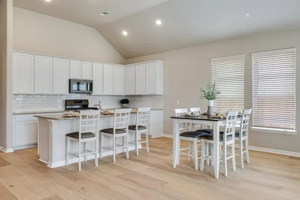 a kitchen with stainless steel appliances granite countertop a table and chairs in it