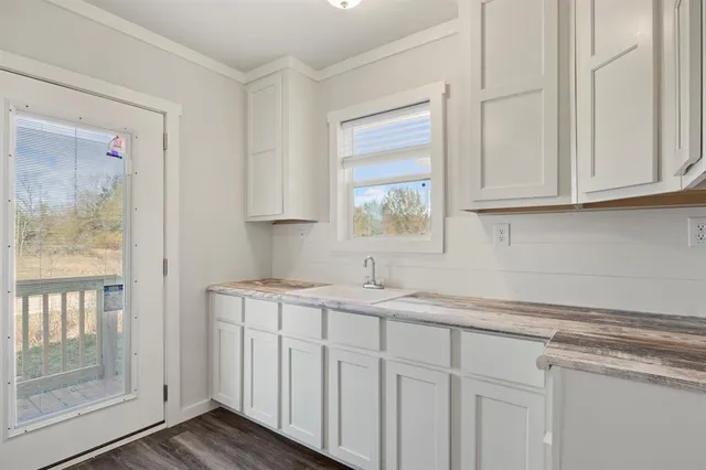 a kitchen with stainless steel appliances granite countertop white cabinets and a window