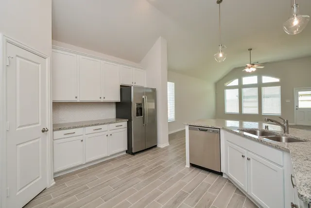 a kitchen with a refrigerator a sink and wooden floor