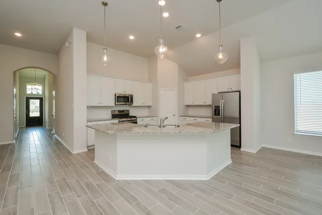 a view of a kitchen with kitchen island a sink stainless steel appliances and cabinets