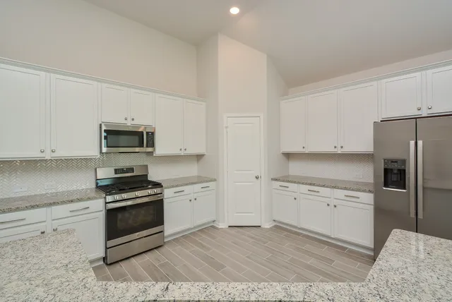 a kitchen with stainless steel appliances white cabinets and a stove top oven
