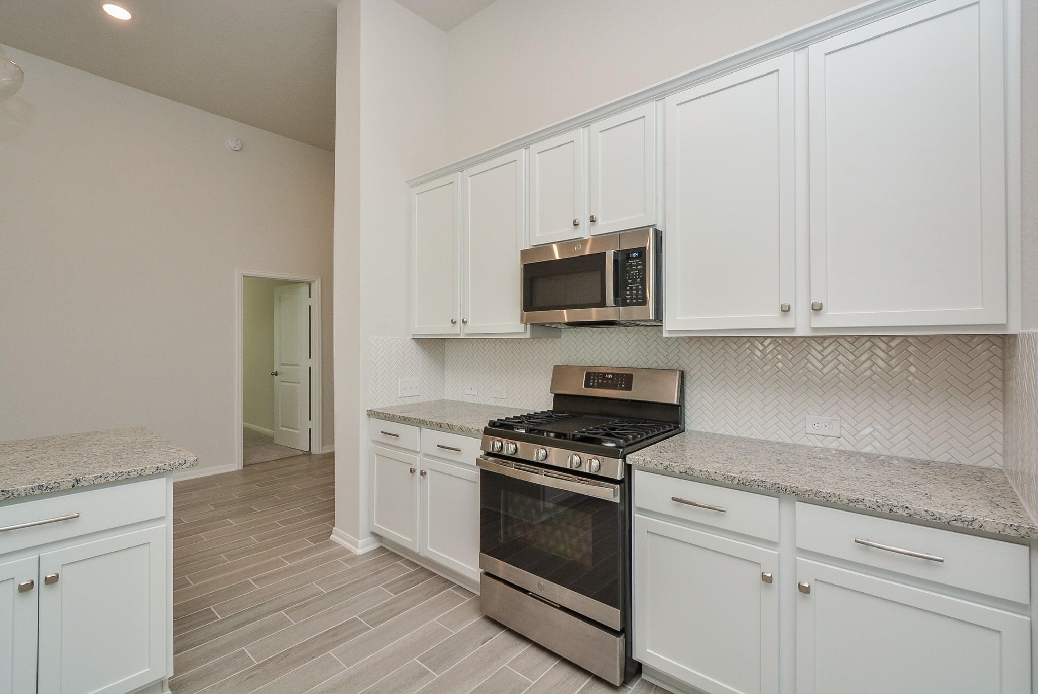 8634 Herring Lane Cypress, TX 77433 - Photo 24 of 50 a kitchen with granite countertop white cabinets and stainless steel appliances