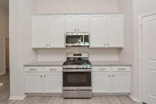 a kitchen with white cabinets and a stove with a sink