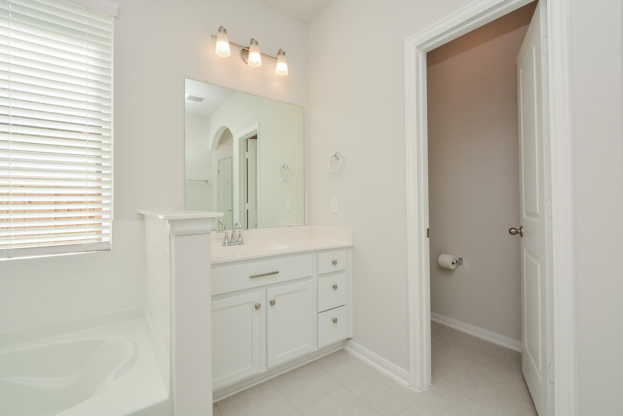 8634 Herring Lane Cypress, TX 77433 - Photo 30 of 50 a bathroom with a double vanity sink a mirror and a bathtub