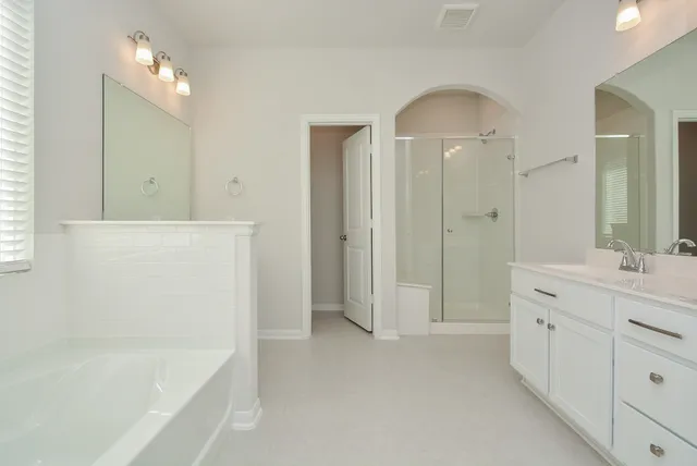 a spacious bathroom with double vanity and a mirror