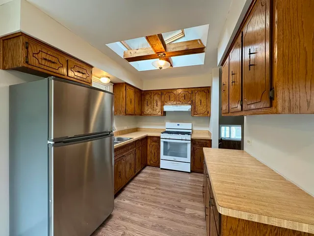 a kitchen with stainless steel appliances granite countertop a refrigerator a stove and a sink with wooden floor