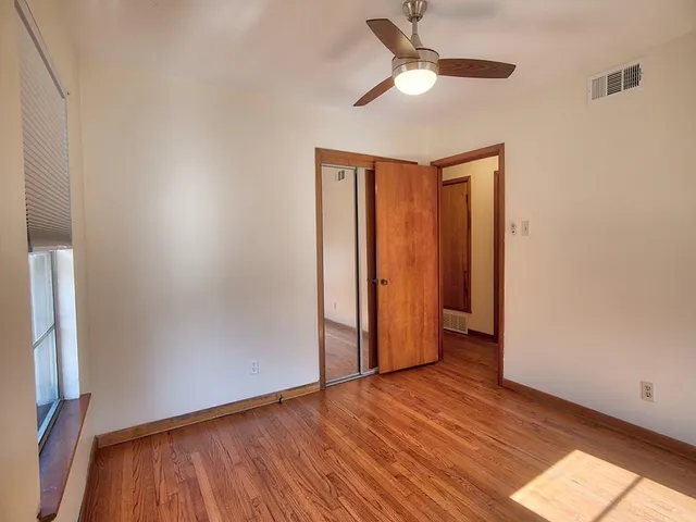 a view of empty room with wooden floor and fan