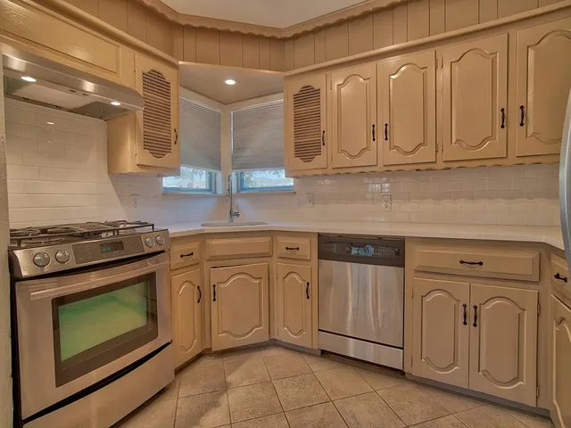 a kitchen with granite countertop white cabinets stainless steel appliances and sink