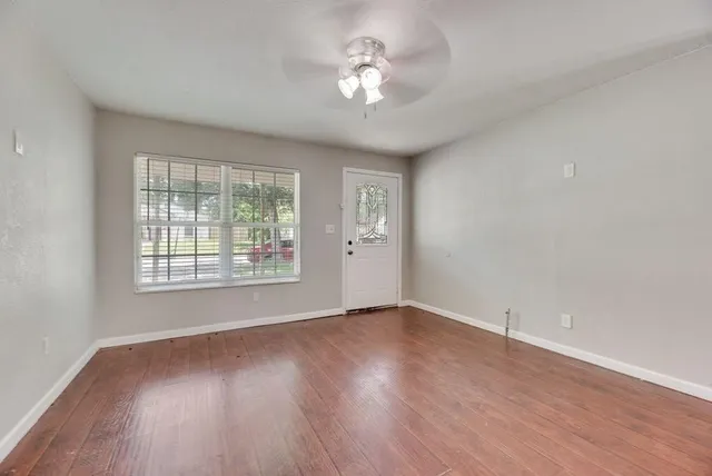 a view of an empty room with a window and wooden floor