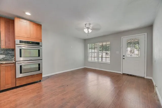a view of a kitchen with a stove wooden cabinets and wooden floor