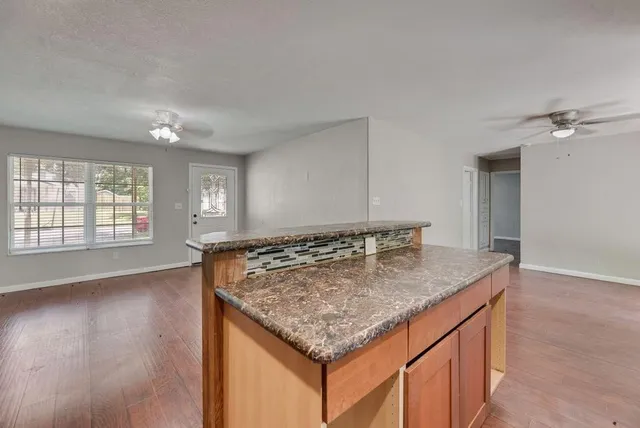 an empty room with kitchen island granite countertop furniture and wooden floor
