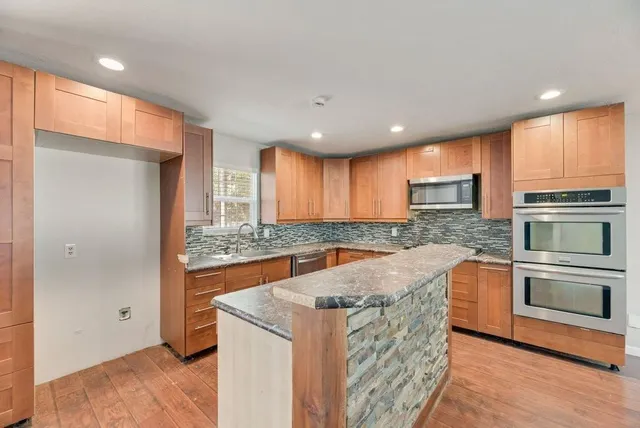 a large kitchen with stainless steel appliances granite countertop a stove a sink and a refrigerator