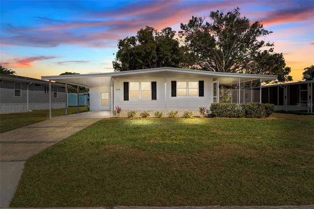 a front view of house with yard and trees in the background