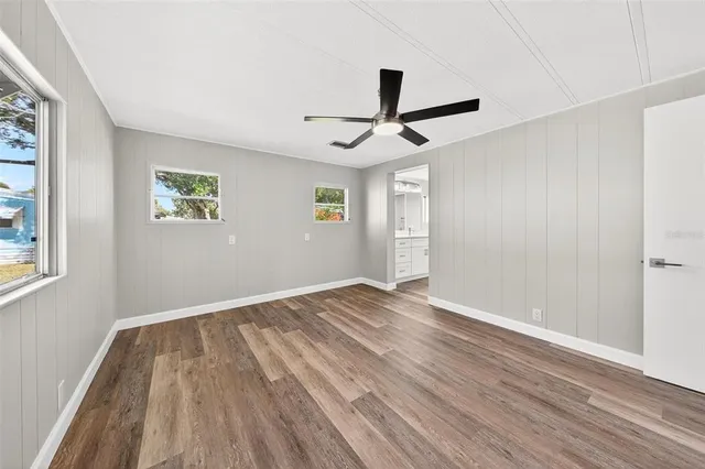 a view of empty room with wooden floor and fan