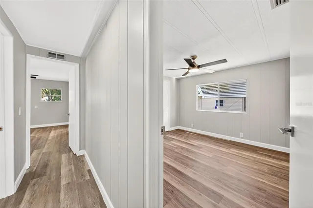 an empty room with wooden floor and ceiling fan