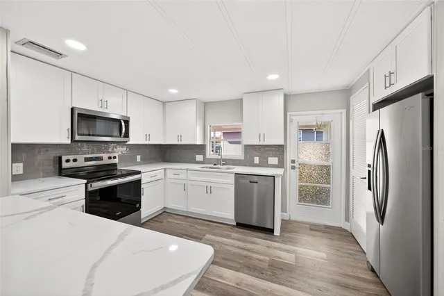 a kitchen with granite countertop a refrigerator stove and microwave