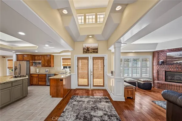 a living room with stainless steel appliances granite countertop furniture wooden floor and a large window