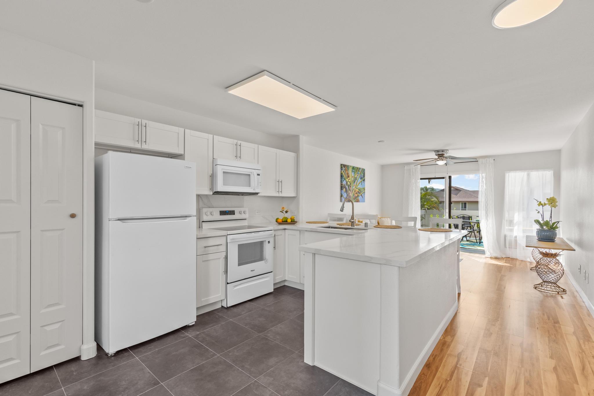 75-6081 Alii Drive, Unit V106 Kailua-Kona, HI 96740 - Photo 3 of 25 a kitchen with white cabinets and white appliances
