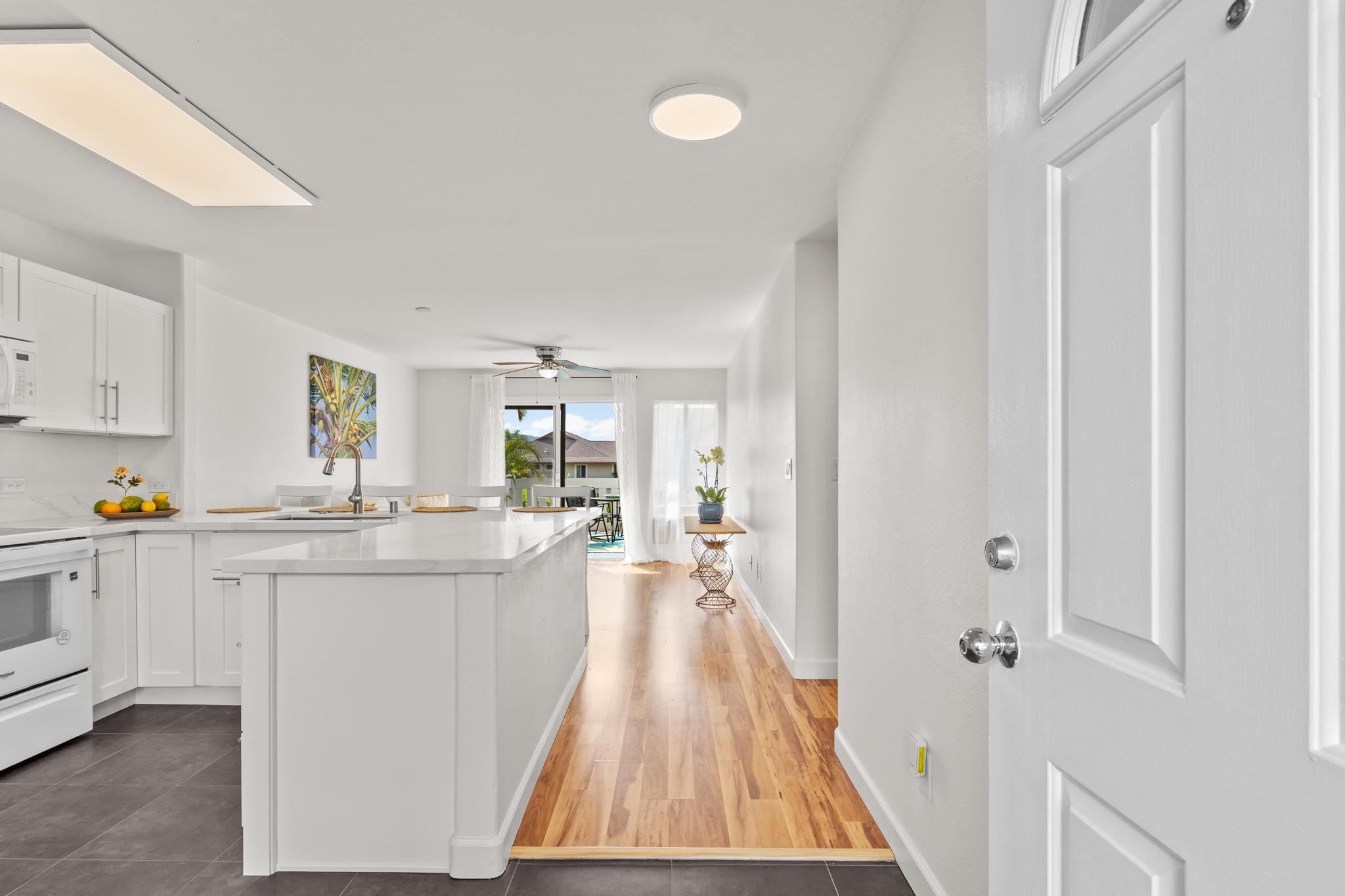 75-6081 Alii Drive, Unit V106 Kailua-Kona, HI 96740 - Photo 5 of 25 a kitchen with kitchen island a white counter top space a sink a view of living room