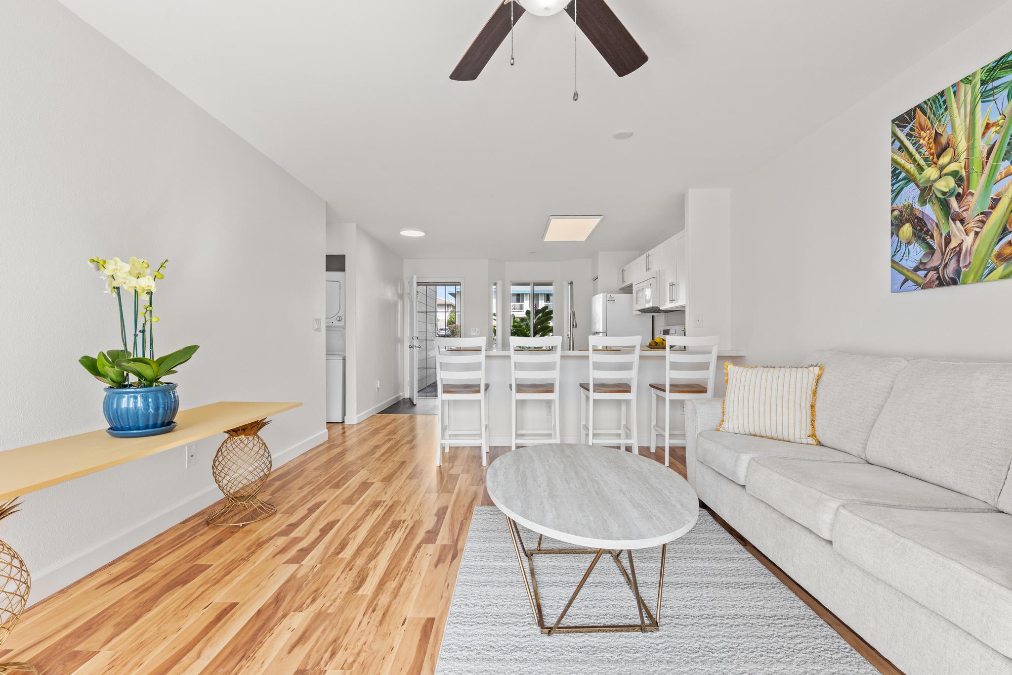 75-6081 Alii Drive, Unit V106 Kailua-Kona, HI 96740 - Photo 7 of 25 a living room with furniture a rug and white walls