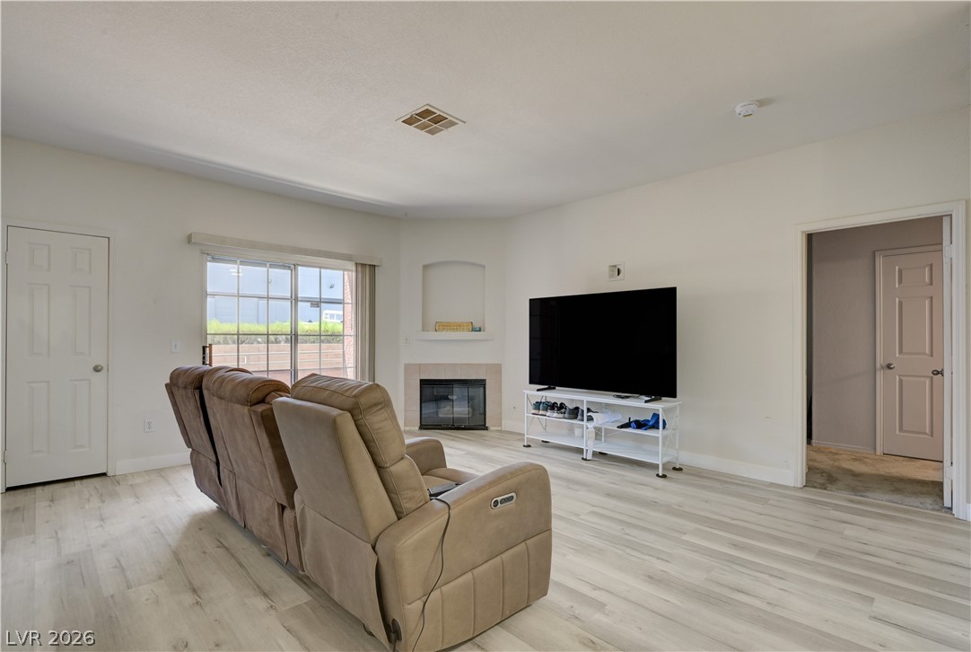 4730 East Craig Road, Unit 1155 Las Vegas, NV 89115 - Photo 4 of 41 A corner fireplace adds warmth to this bright living area with plank flooring and sunlit windows.