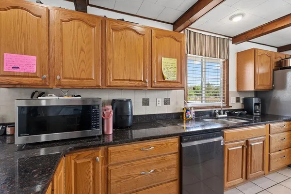 a kitchen with granite countertop a sink stainless steel appliances wooden floor and a window