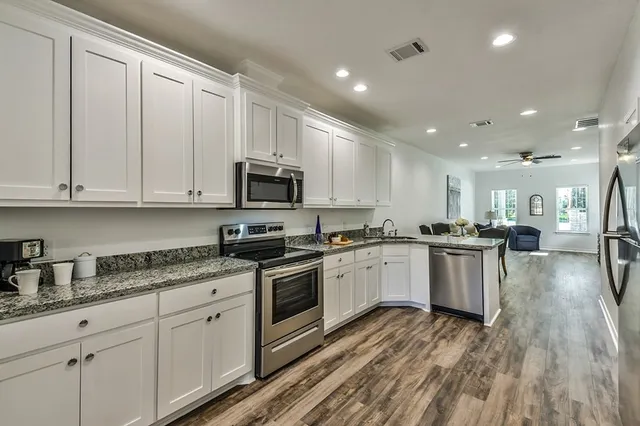 a kitchen with granite countertop white cabinets and stainless steel appliances