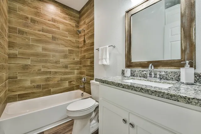 a bathroom with a granite countertop toilet sink and mirror
